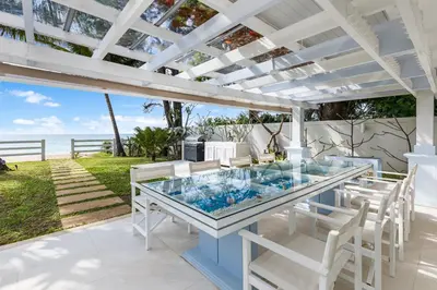a patio with a glass table and white chairs at Carpe Diem Beach Villa in Natai Beach