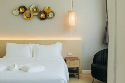 a bedroom with a white bed and a black chair at Kamala Havana Hotel and Cafe in Kamala Beach