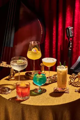 a table topped with glasses of drinks and a guitar at Kamala Havana Hotel and Cafe in Kamala Beach