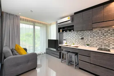 a living room with a kitchen with a couch and a tv at City Gate Kamala D305 by Phuket Sabay Rent in Phuket Town