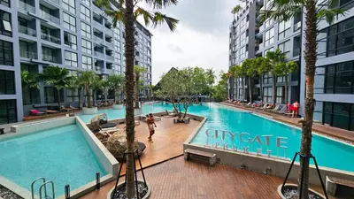 a swimming pool with palm trees and buildings at City Gate Kamala D305 by Phuket Sabay Rent in Phuket Town