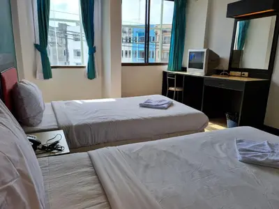 a hotel room with two beds and a television at Desa Phuket in Phuket Town