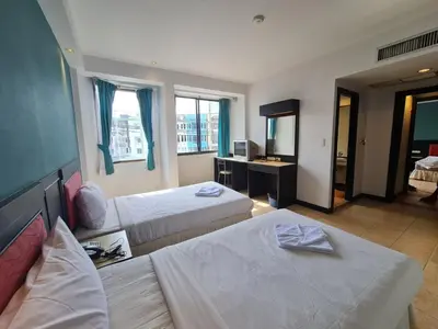 a hotel room with two beds and a mirror at Desa Phuket in Phuket Town