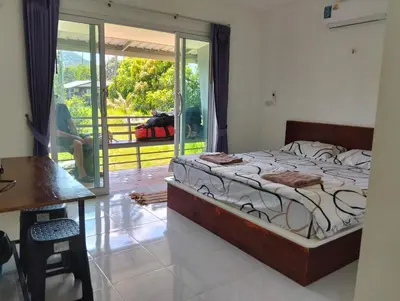 a bedroom with a bed and a table and a balcony at Firdous Guesthouse in Ko Yao Yai