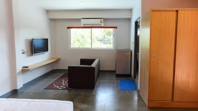 a room with a chair and a tv and a window at Bangtao Guest House in Bang Tao Beach