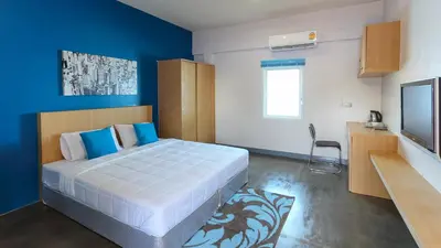 a bedroom with a large bed and a blue wall at Bangtao Guest House in Bang Tao Beach