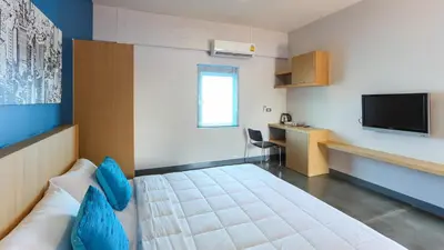 a small room with a bed and a television at Bangtao Guest House in Bang Tao Beach