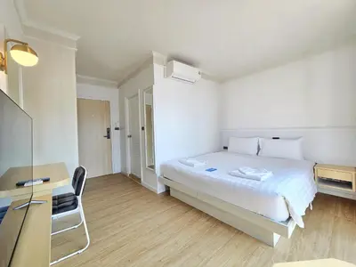 a white bedroom with a bed and a desk at Sira Boutique, Patong in Patong Beach