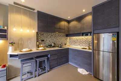 a kitchen with wooden cabinets and a stainless steel refrigerator at Stylish apartments Kamala CityGate in Kamala Beach