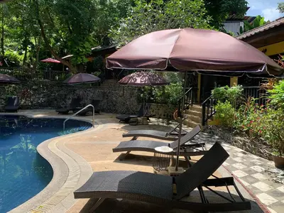 a swimming pool with lounge chairs and an umbrella at the hill resort \u5e0c\u5c14\u5ea6\u5047\u5c4b in Patong Beach
