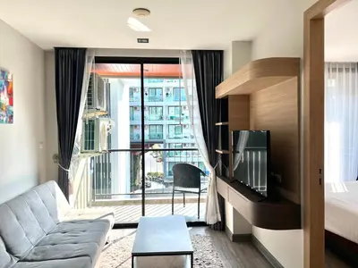 a living room with a couch and a large window at Modern style 1BR Condo close to Kata beach in Kata Beach