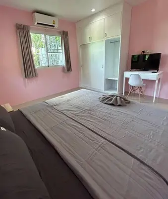 a large bed in a bedroom with a pink wall at Villa Patong in Ban Na Nai