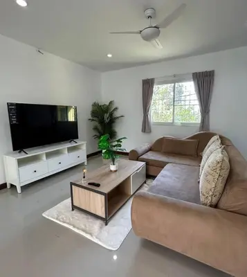 a living room with a couch and a flat screen tv at Villa Patong in Ban Na Nai