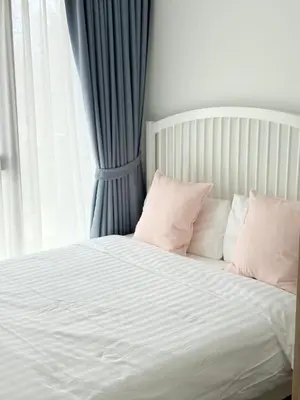 a white bed with pink pillows and a window at Skypark Laguna Phuket in Bang Tao Beach