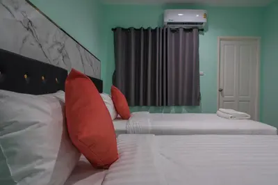 a bedroom with two beds with red and white pillows at Anatasia Apartment Phuket in Phuket Town
