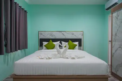 a bedroom with a white bed with two swans on it at Anatasia Apartment Phuket in Phuket Town