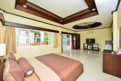 a bedroom with a large bed and a living room at Group Getaway Patong House in Patong Beach