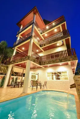 a house with a swimming pool in front of a building at Group Getaway Patong House in Patong Beach