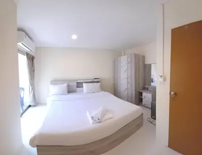 a white bedroom with a large bed with white sheets at Lucky Seven Patong in Patong Beach