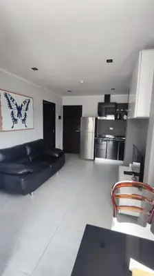 a living room with a black couch and a kitchen at 1bed in Chalong