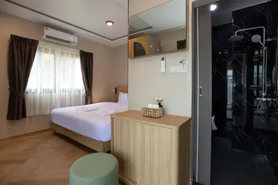 a small room with a bed and a shower at Tuna Boutique Hotel Patong in Patong Beach