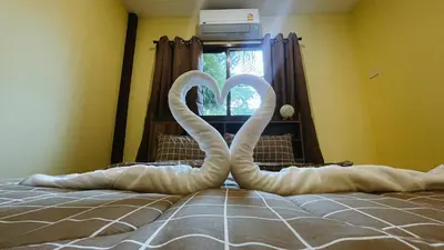 two swans shaped like hearts are on a bed at Blackberry in Rawai Beach