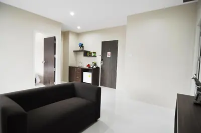 a living room with a black couch and a kitchen at Khao Rang Place in Phuket Town