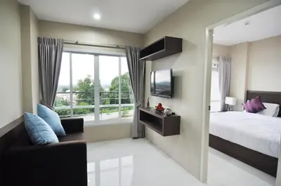 a bedroom with a bed and a tv and a window at Khao Rang Place in Phuket Town