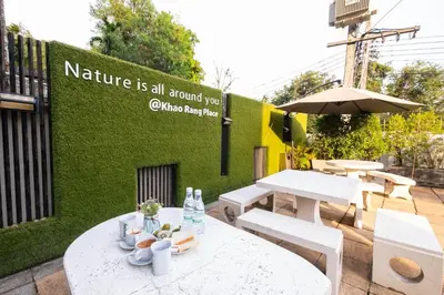 a patio with white tables and chairs and a green wall at Khao Rang Place in Phuket Town