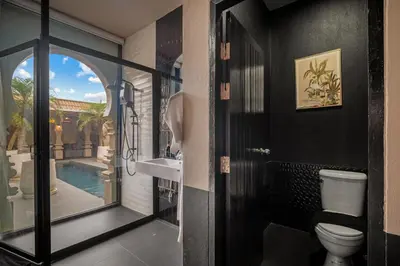 a bathroom with a toilet and a sink and a pool at Marococco Private Pool Villa in Ban Mut Dok Khao