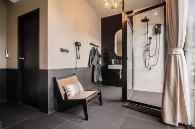 a bathroom with a shower and a chair next to a sink at Marococco Private Pool Villa in Ban Mut Dok Khao