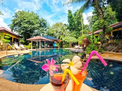 a drink sitting on a table next to a swimming pool at beautiful pool house in Patong Beach