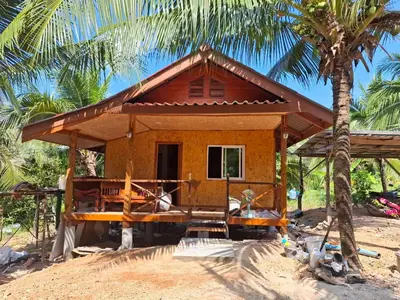 a small house on the beach with a palm tree at ฟาดิลบังกะโล Fadel bungalow in Ban Lo Pa Ret