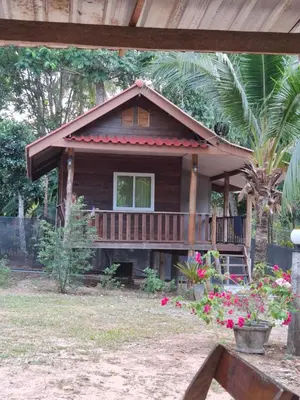 a house with a porch and flowers in front of it at ฟาดิลบังกะโล Fadel bungalow in Ban Lo Pa Ret