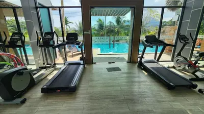 a gym with several treadmills and a swimming pool at Plus condominium 2 kathu in Kathu