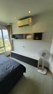 a bedroom with a bed and a table and a window at Plus condominium 2 kathu in Kathu