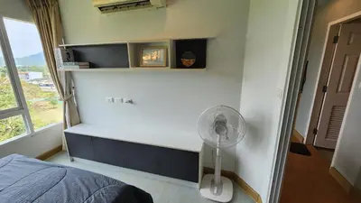 a bedroom with a bed and a fan and a window at Plus condominium 2 kathu in Kathu