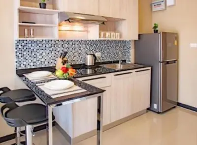 a kitchen with a counter with plates and a refrigerator at Nai Harn NBC 1 BR in Rawai Beach