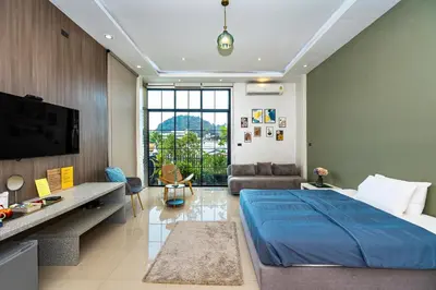 a bedroom with a blue bed and a living room at Ellie House Phuket Old Town in Ban Rangeng
