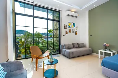 a living room with a couch and a large window at Ellie House Phuket Old Town in Ban Rangeng