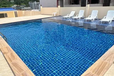 a large swimming pool with chairs and blue water at 1 bed condo, No.1 location, next to Patong Beach. in Patong Beach