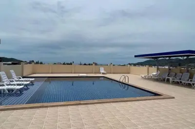 a swimming pool on a roof with chairs and a umbrella at New 1 bed condo, very best central area, Patong in Patong Beach