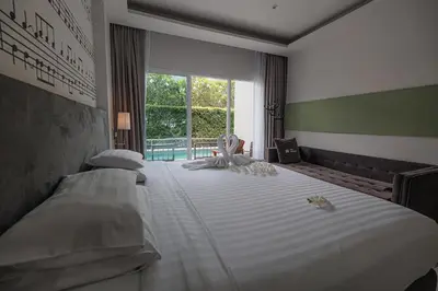 a bedroom with a large white bed with a window at The Melody Phuket Kata Beach in Kata Beach