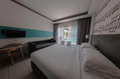 a bedroom with a large white bed and a desk at The Melody Phuket Kata Beach in Kata Beach