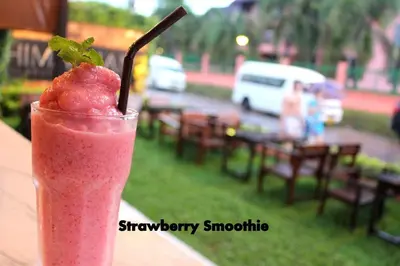 a drink sitting on a table with a strawberry smoothie at Himaphan Boutique Resort - SHA EXTRA PLUS in Nai Yang Beach