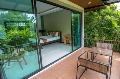 a room with a balcony with a bed and a table at Himaphan Boutique Resort - SHA EXTRA PLUS in Nai Yang Beach