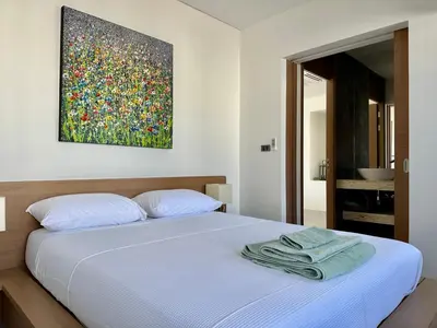 a bedroom with a bed with a painting on the wall at Villa Amata in Phuket Town