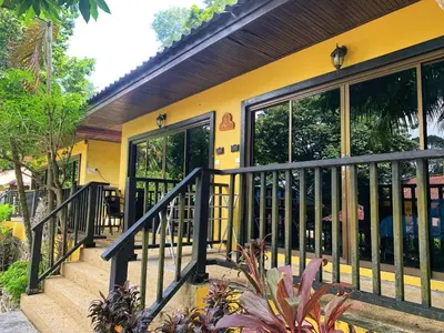 a yellow house with a balcony with glass doors at patong beautiful pool villa in Patong Beach