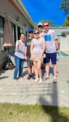 a group of people standing in front of a house at Aonang Peace Pool Villa in Ban Khlong Haeng