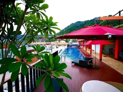 a pool with tables and umbrellas next to aocked at 7Q Patong in Patong Beach